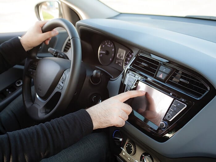Mann, der einen Touchscreen eines Infotainmentsystems im Auto bedient.