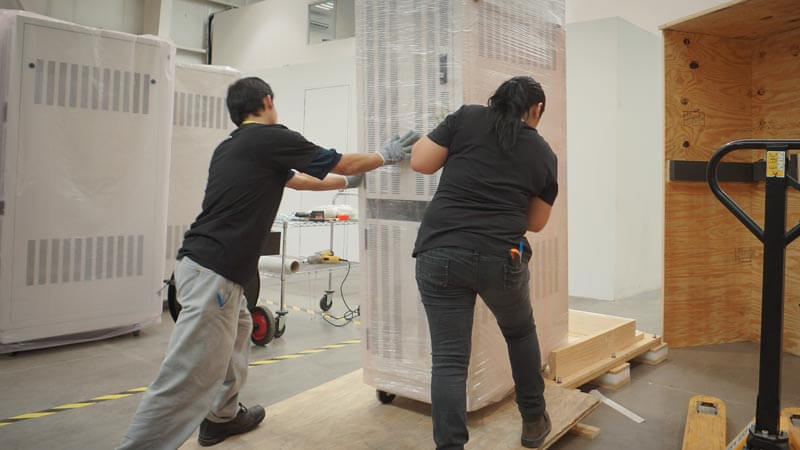 Employees moving properly packed equipment into a crate